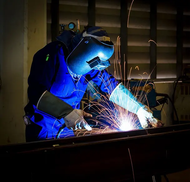 A person welding in the dark with blue light